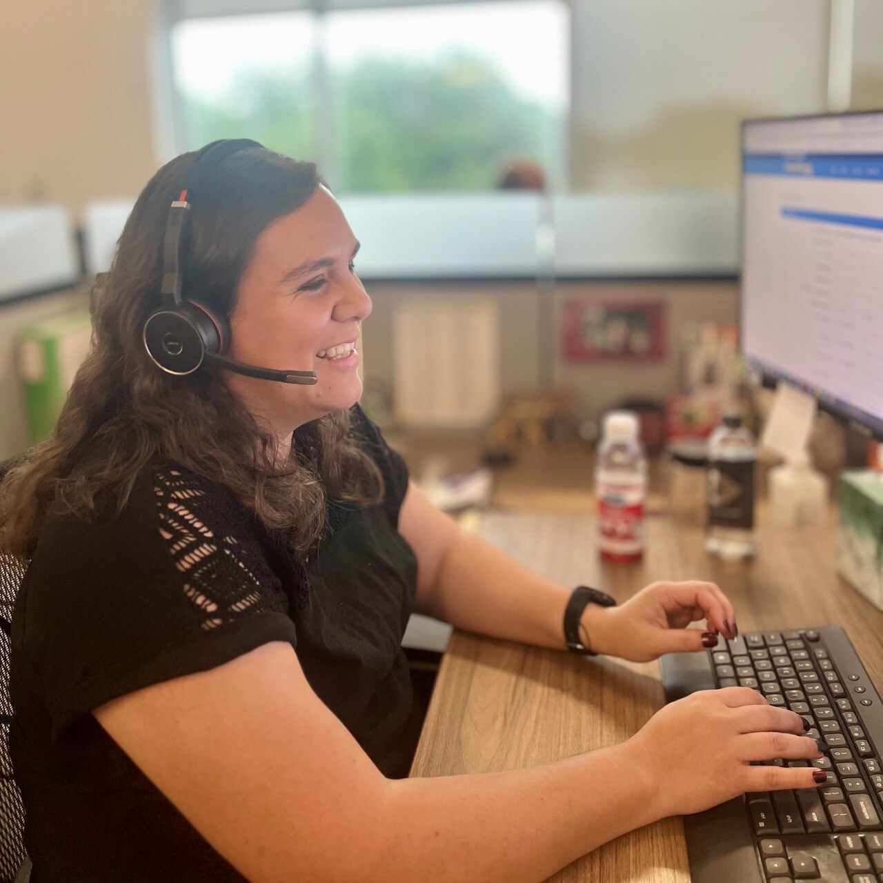 A female employee with headset on helping customers behind a computer 