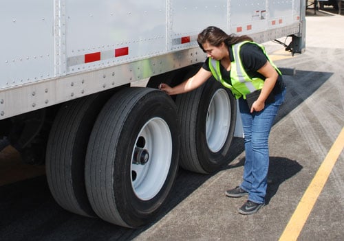 A women checking the tires on a premier trailer leasing trailer for maintenance 